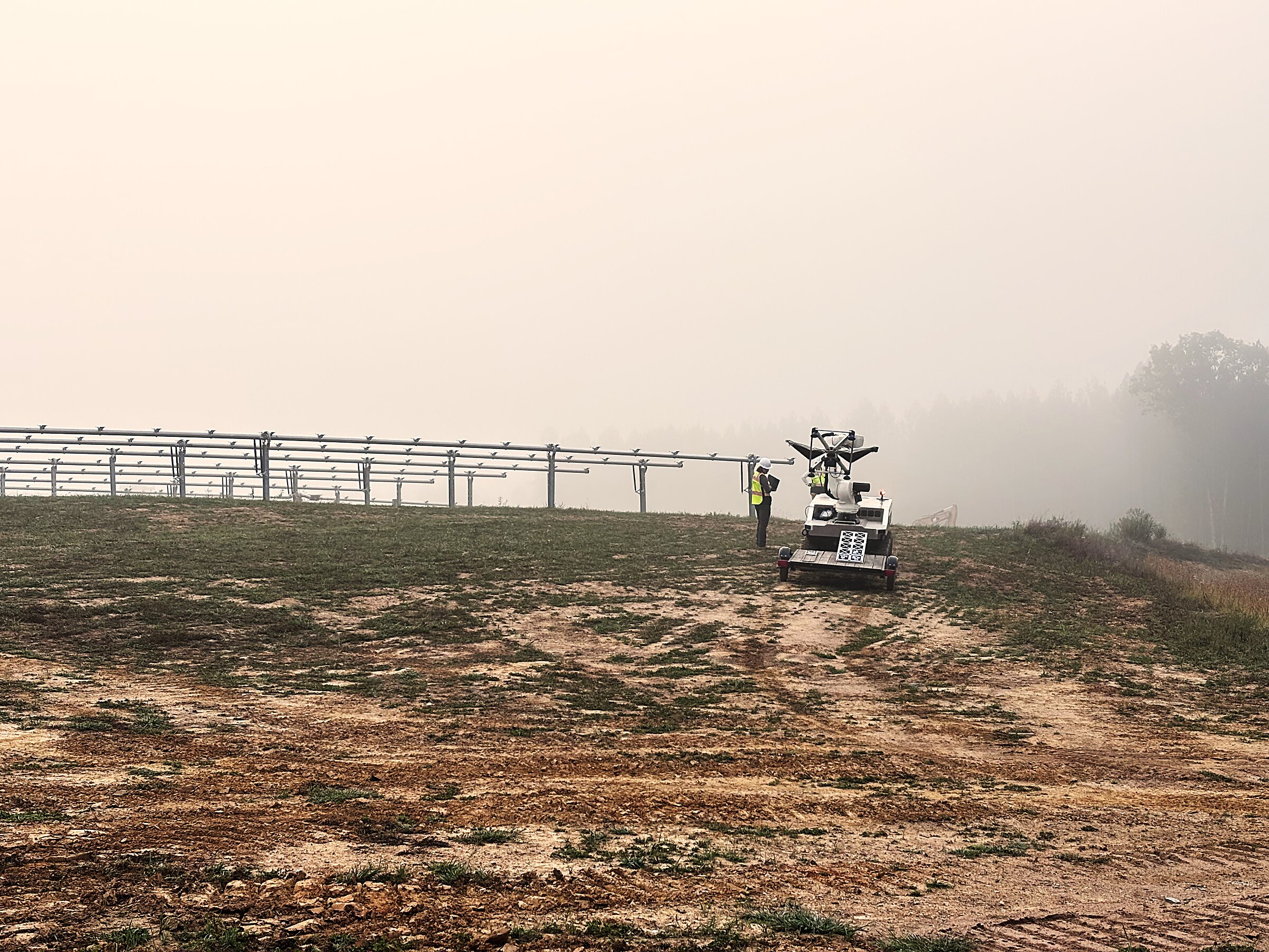 A Cosmic autonomous platform and technician on a solar construction site at dawn